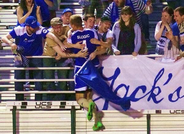A group of soccer fans catching the player Patrick Slogic.