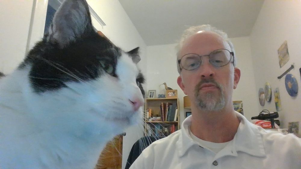 A man and a black and white cat stare at the camera