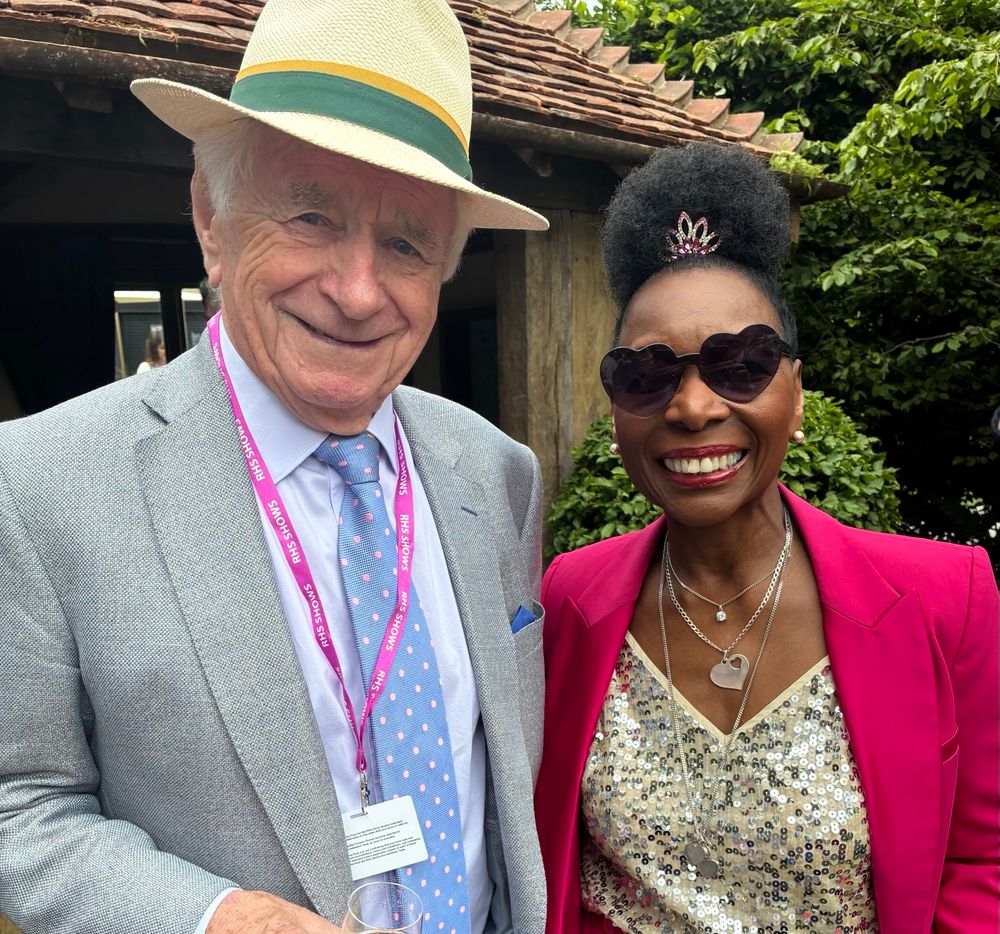 Johnny Ball, the loveliest granddad you’ve ever seen, stands on the left in a nice suit and hat holding a glass of champagne. Floella Benjamin, the loveliest granddad you’ve grandma you’ve ever seen, stands on the right looking glam in a sparkly top and heart shaped sunglasses. They are wonderful. 