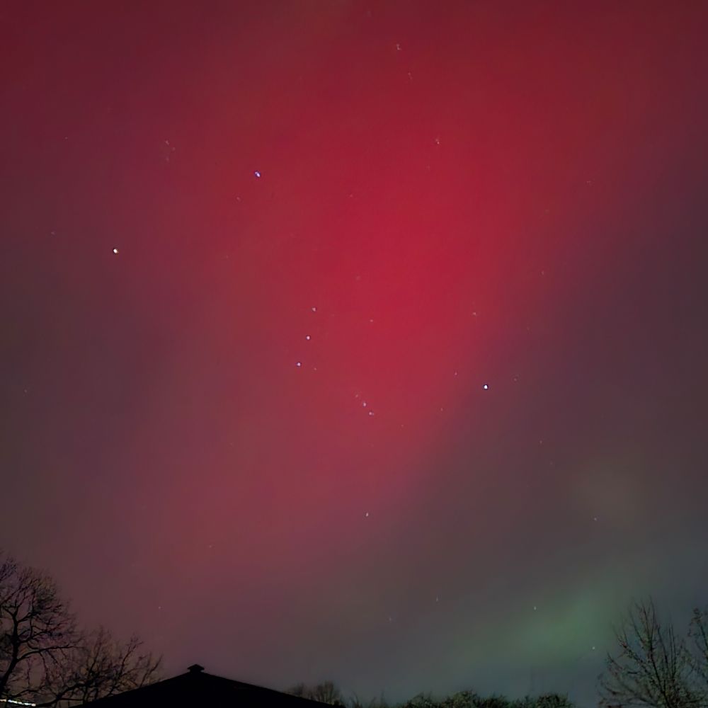 Image of northern lights 11/11/25 looking southeast near St. Paul, MN, deep red color with green aurora on the horizon. Orion's Belt can be seen in the center.