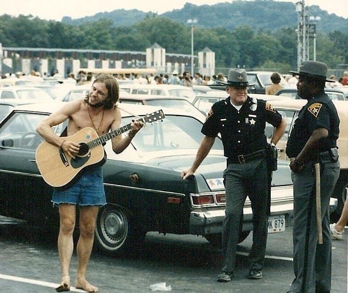 barefoot and shirtless deadhead serenades two police officers on guitar, parking lot of the Rubber Bowl, Akron Ohio 6/30/86