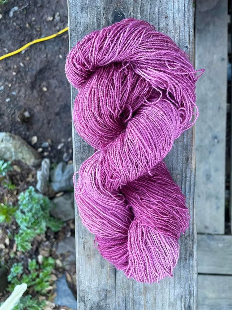A skein of bright pink wool lying on a wooden table. 