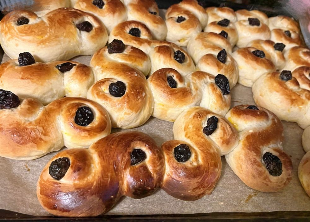 A picture of buns made with saffron and painted with egg yolk, with raisins in. They’re called lussekatter and originate from Sweden based on Saint Lucia from Italy.