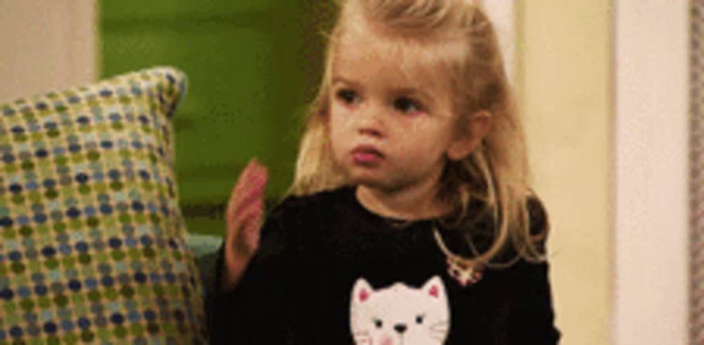 a little girl wearing a black cat shirt is clapping her hands