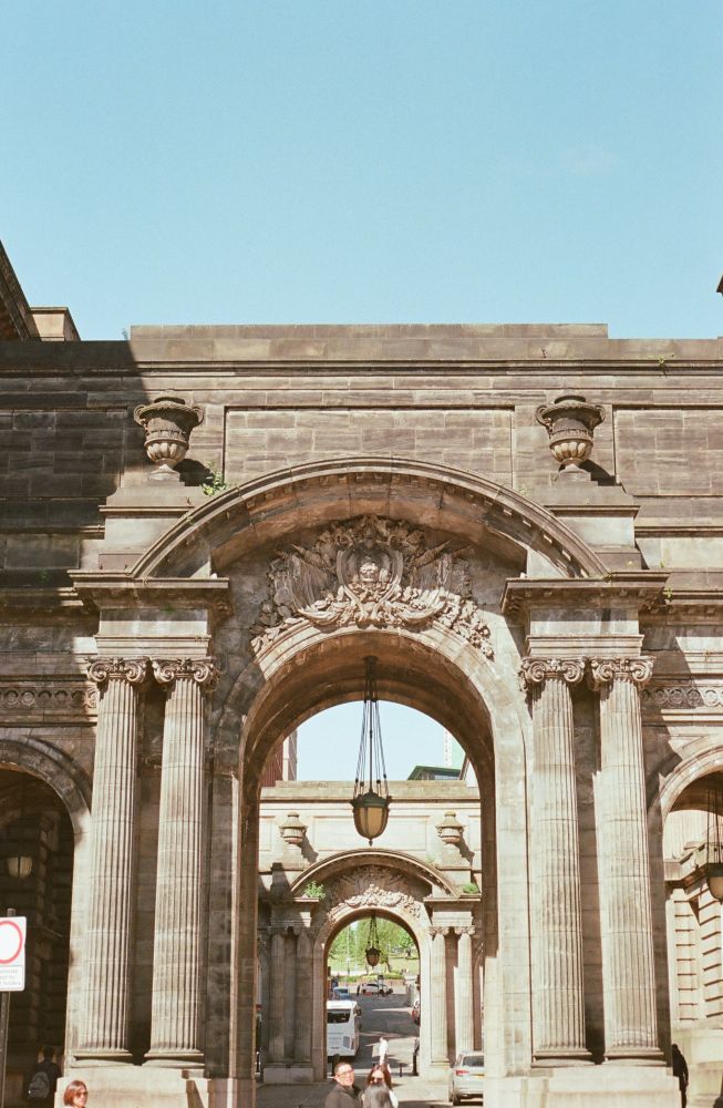 A picture of two concentric archways in glasgow city center, flanked by four columns each and with large wrought-iron lanterns hanging in the middle from chains 