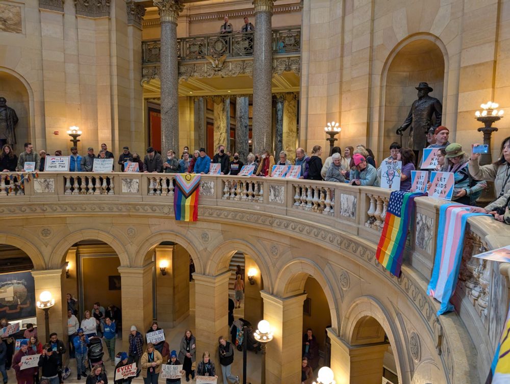 MN capitol rotunda with various pride flags and people