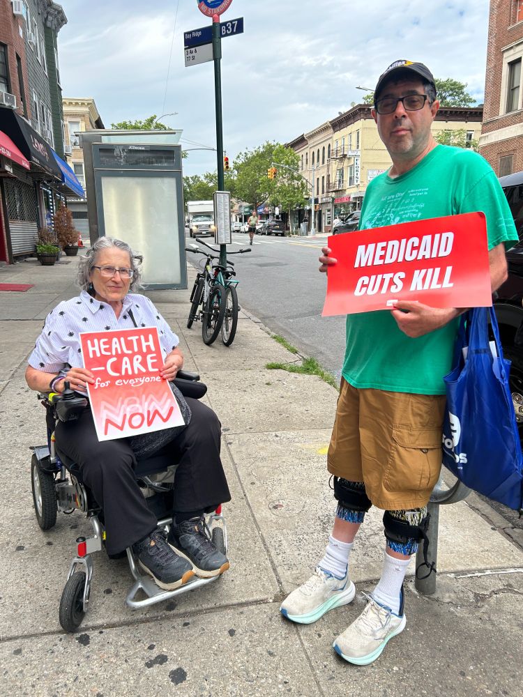 Advocates holding Medicaid signs on sidewalk.