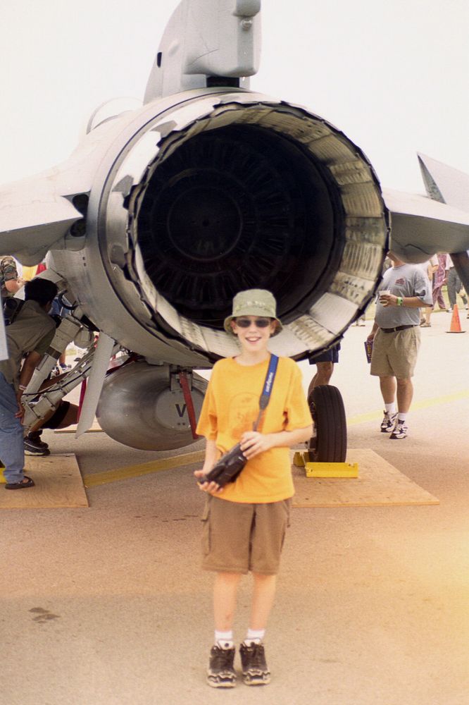 me at age ~11, standing behind an F-16 holding a Sony Handycam