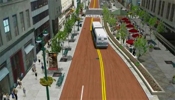 Red busway on NYC street, with a bus driving down it and wide sidewalks on either side