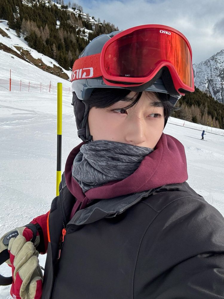 kpop group ateez member choi san in a selfie in snowboarding gear at a ski resort