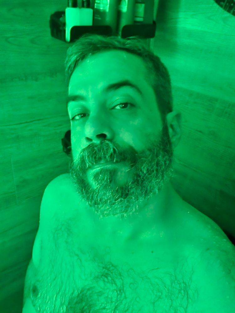 Naked man in the shower. Lit only in green and visible from mid chest up. He attempts to put a valiant face on the Monday Moody. 