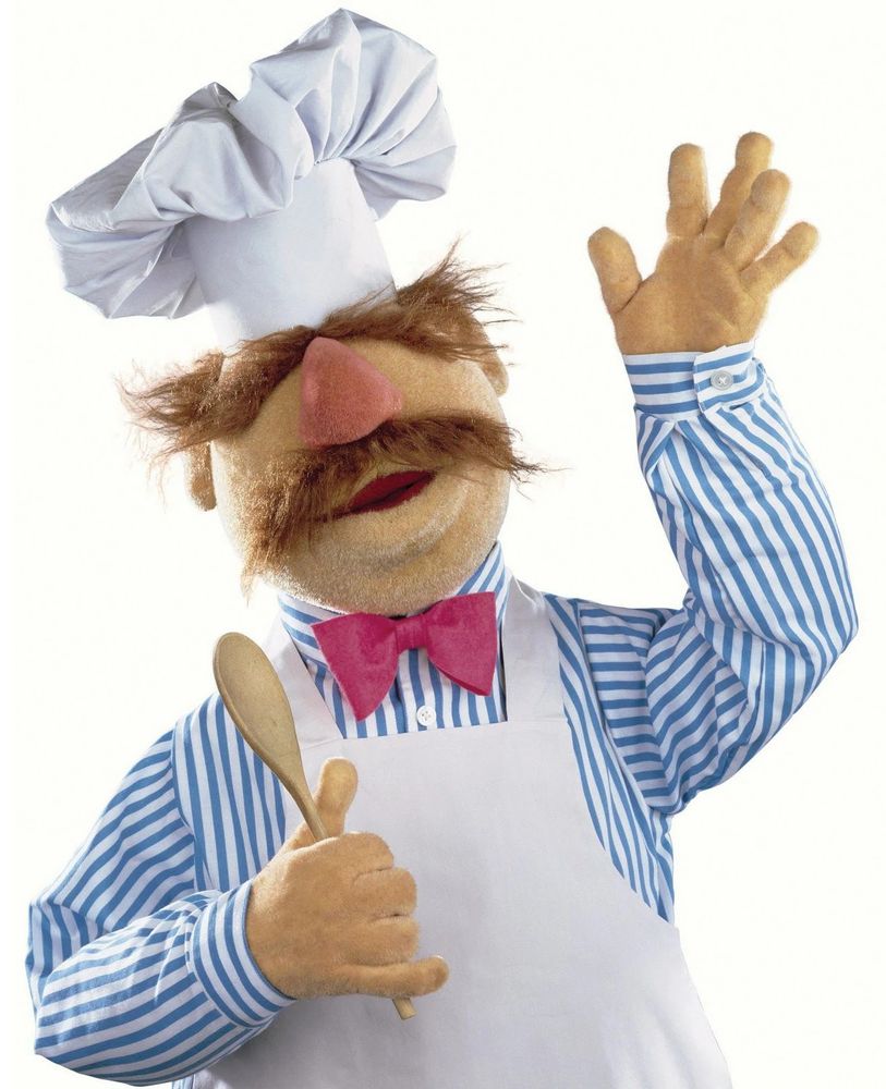 ID: The Swedish Chef wears a chef's hat and carries a wooden spoon, holding a hand up in a wave.