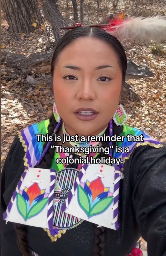 An native woman in regalia explains 

This is just a reminder that
"Thanksgiving" isa colonial holiday…