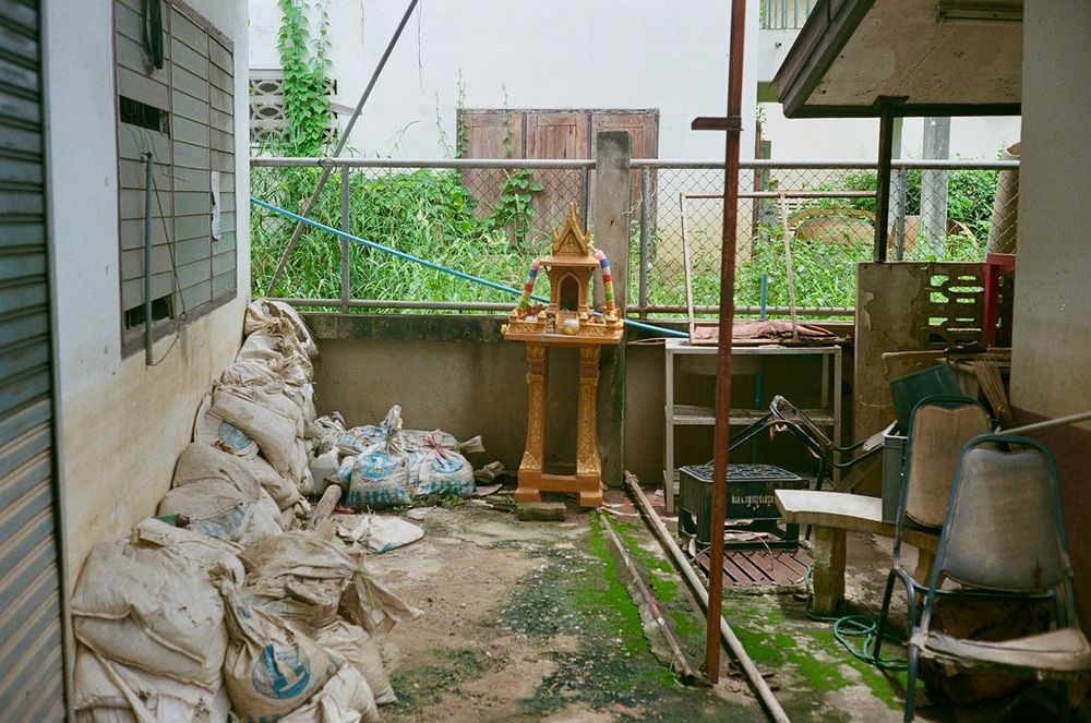 A “spirit house” amongst sandbags and other clutter behind a house