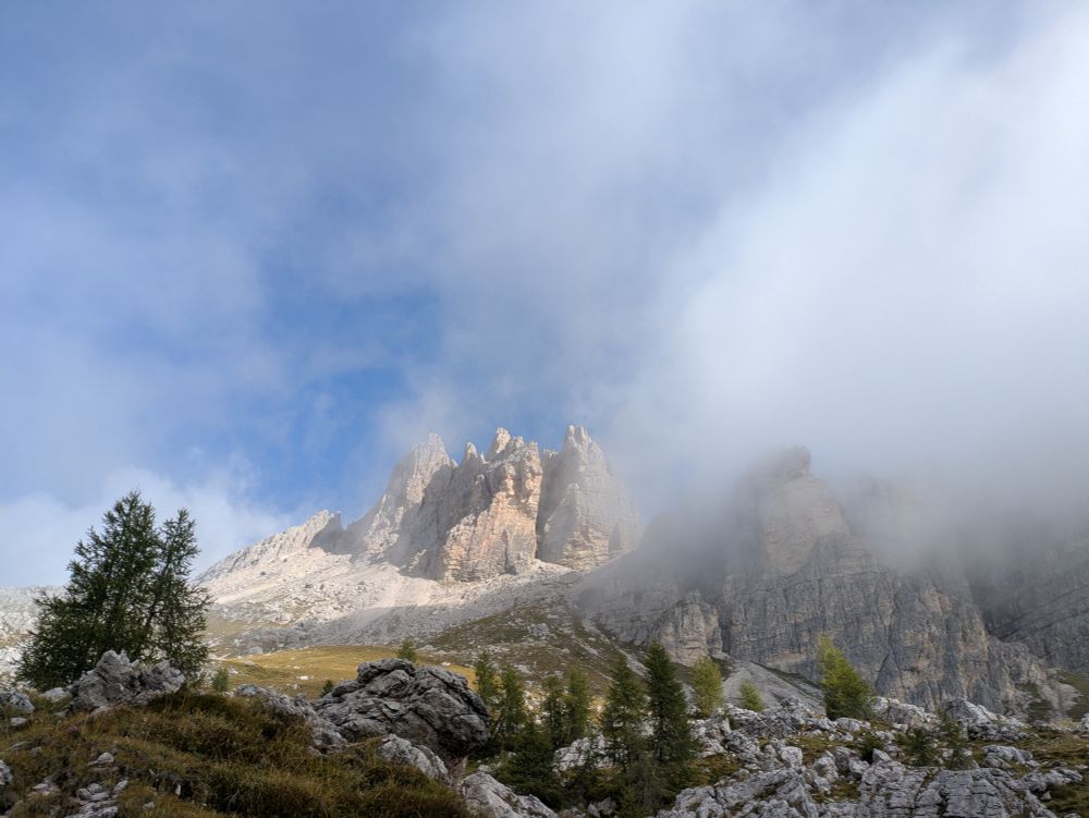 Sun shines through the clouds on a cluster of peaks in the Dolomites.