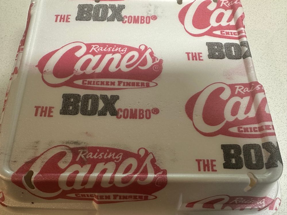 Picture of a styrofoam food container from the restaurant Raising Cane’s. Inside it contains “The Box Combo”