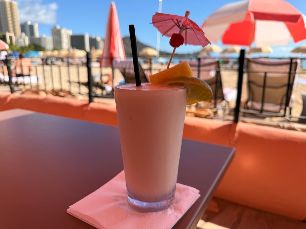 Picture of a pina colada at a beachside table. On a sunny day in Honolulu, Hawaii. Waikiki beach