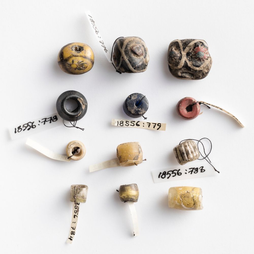 twelve glass beads in yellow, blue and earthy tones - some of them have a lot of detail and patterns in them