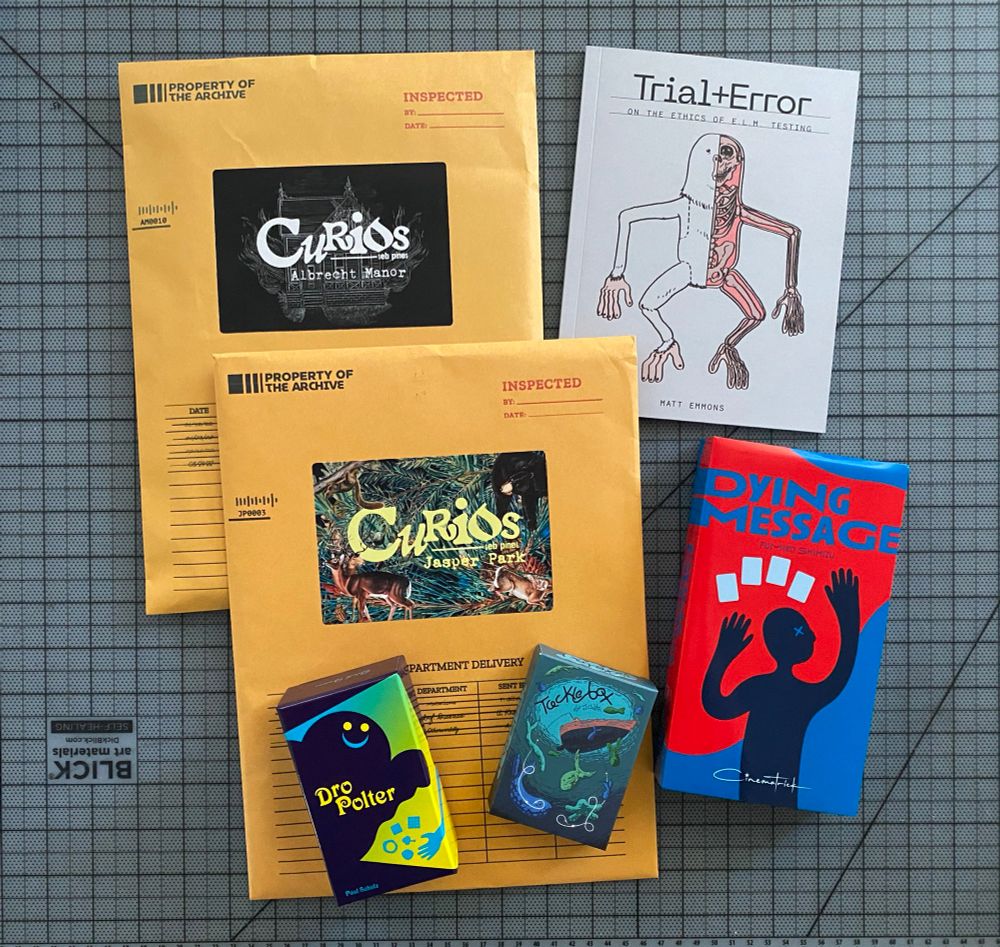 Photo of some games (and a comic book). Curios Albrecht Manor, Curios Jasper Park, Tacklebox, DroPolter, Dying Message, and Trial+Error