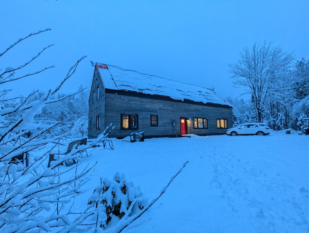 Snowbound House in the blue twilight with a few warm yellow windows 