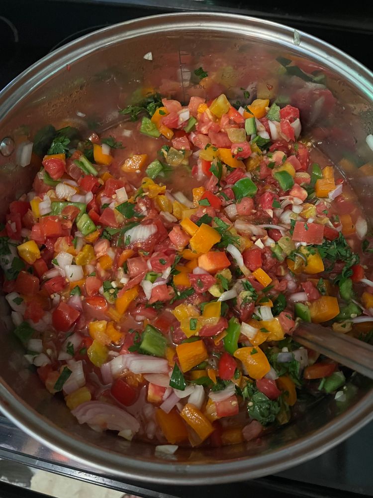 A large pot of chopped vegetables: tomatoes, onions, peppers, jalapenos and cilantro all mixed up and ready to be cooked down into salsa for canning.