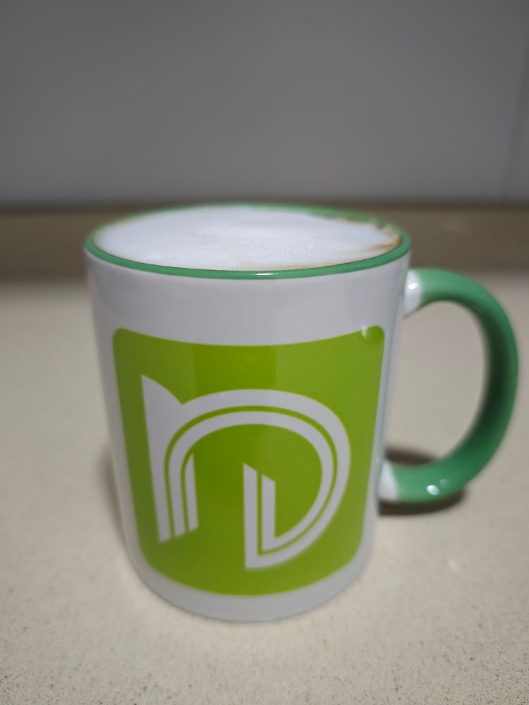 A green and white coffee mug with the nCine logo.
