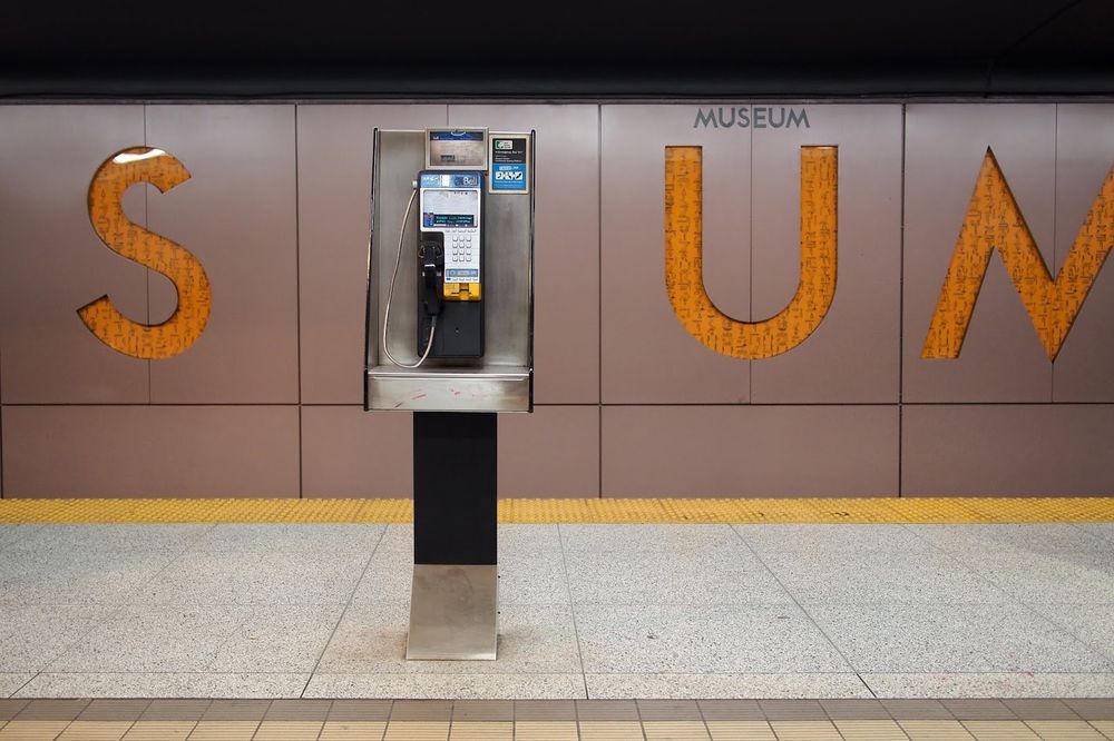 Museum Subway Station platform with a pubic telephone on the centre and a part of the “museum” sign behind.  