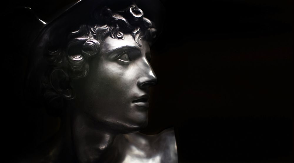 A Neoclassical black basalt bust of Mercury by Wedgwood, seen in profile against a black background. The god is depicted with youthful, idealized features, wearing a winged helmet that marks him as the swift messenger of the gods. Made from matte black basalt stoneware, the bust combines classical elegance with 18th-century industrial craftsmanship.