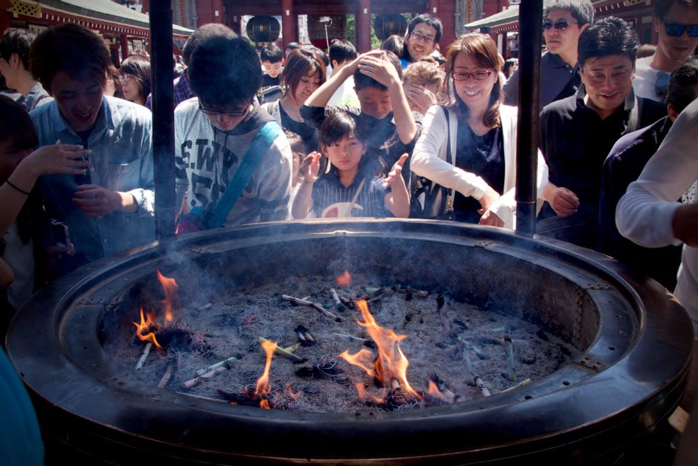 People gathering around a jōkōro (a large urn) with intense wafting in the air.