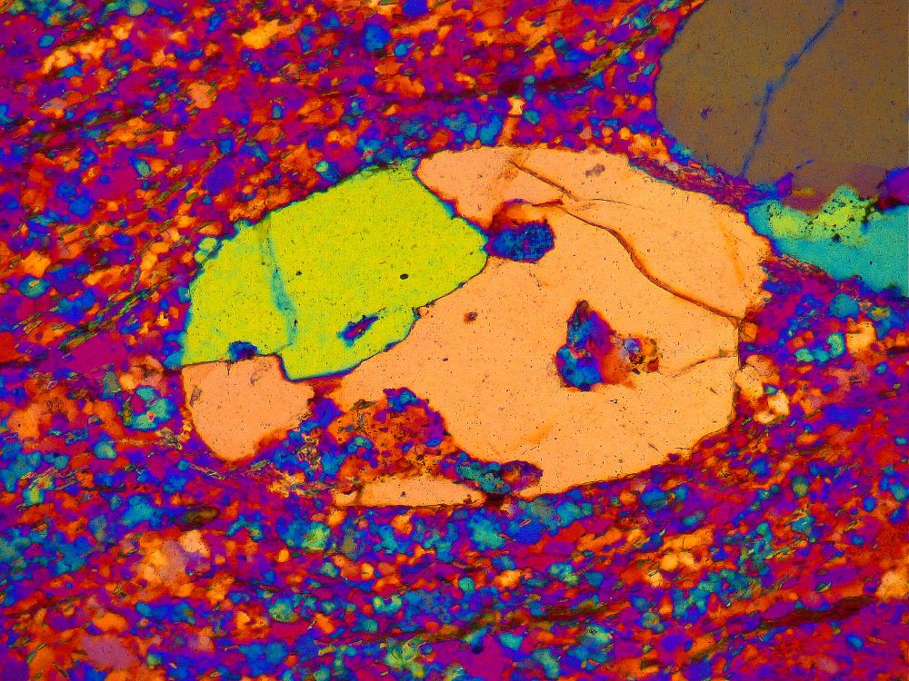 a quartz grain in a thin section (a polished rock slab mounted on glass), resembling a face, as seen under the petrographic microscope