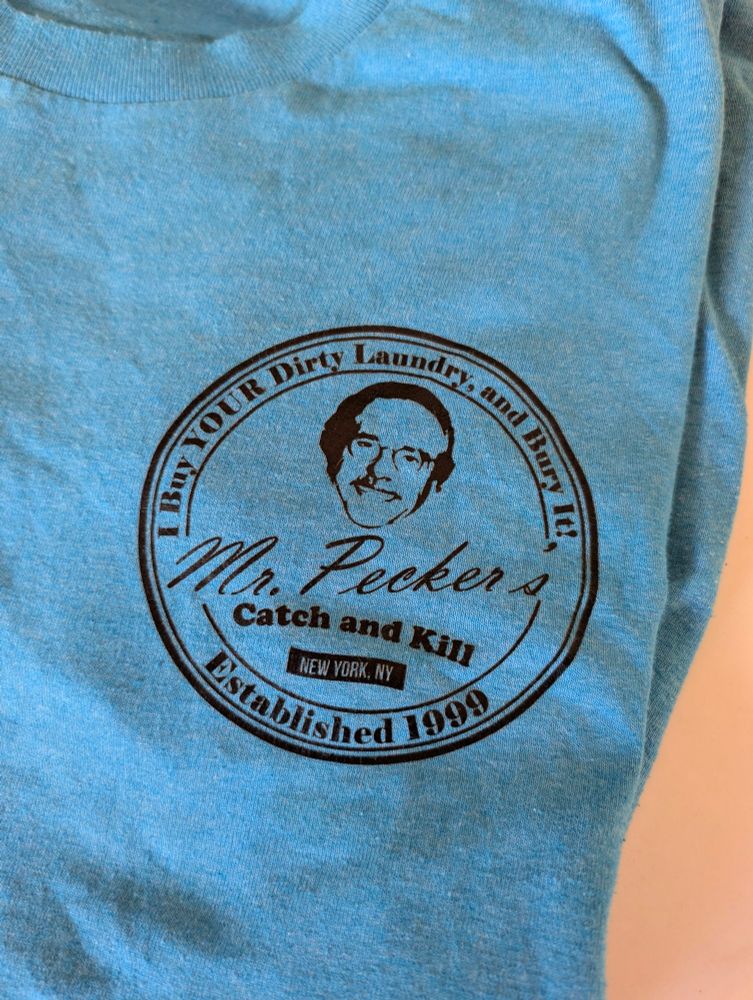 A t-shirt with David Pecker and the phrase "Mr. Pecker's catch and kill. I buy your dirty laundry and bury it. Established 1999"