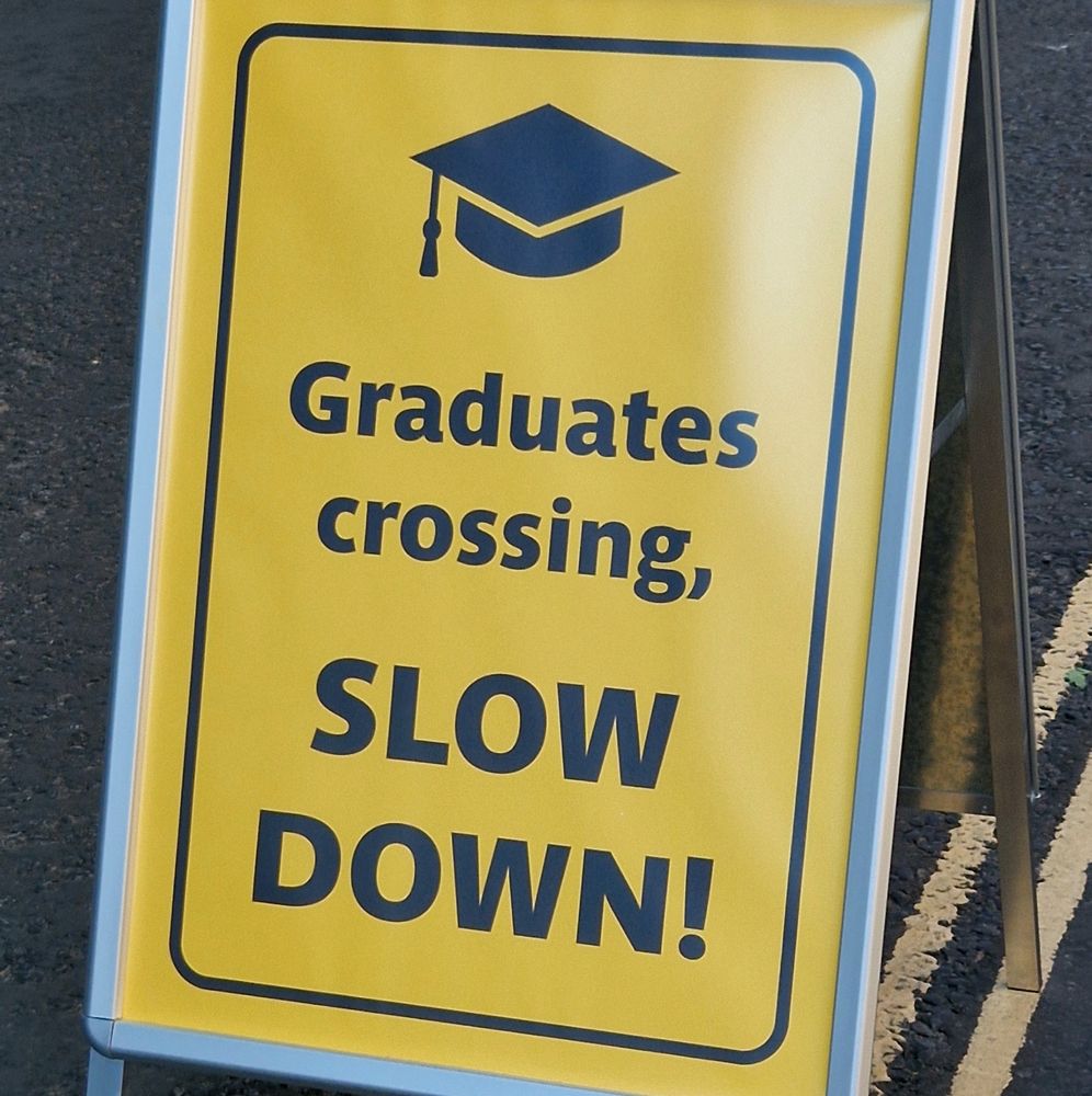 Sign warning drivers of hapless graduates who don't know how to cross a road safely. 