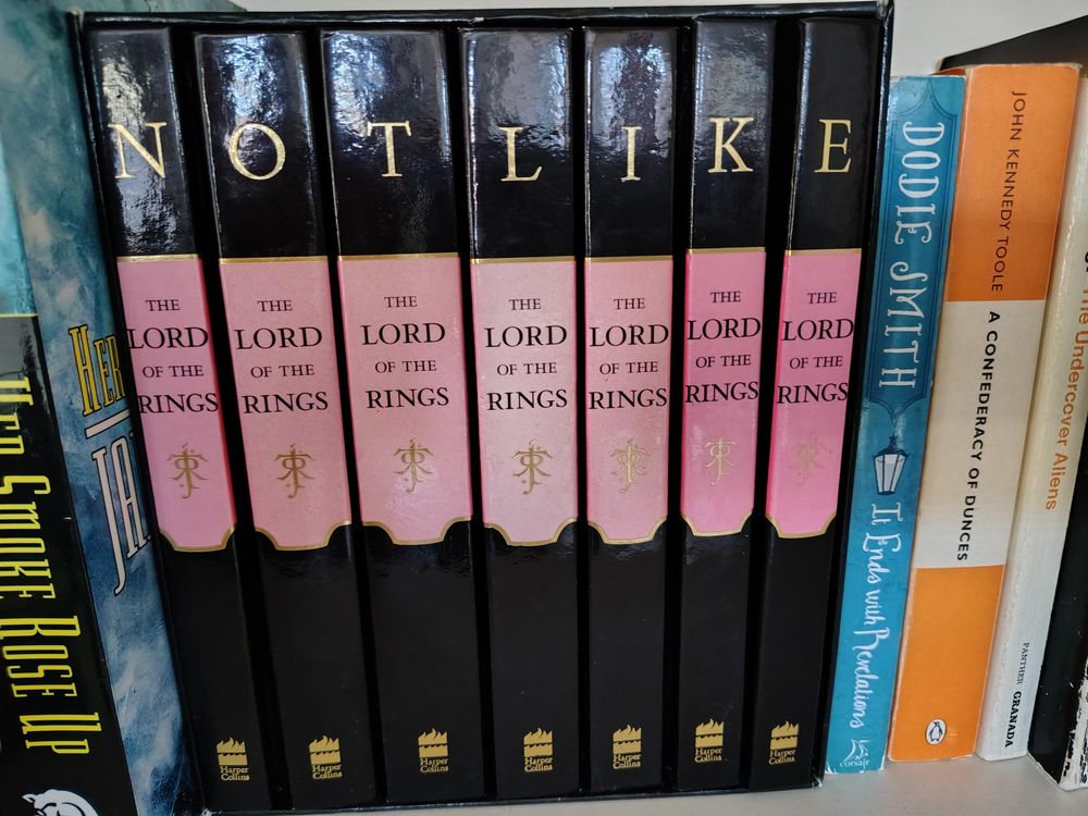 A box of seven Lord of the Rings books (two volumes for each book, plus one of extra material), with the spines each displaying one letter of the name TOLKIEN. They have been rearranged to spell NOT LIKE.