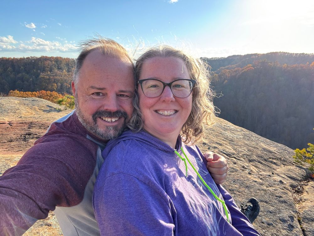 My husband taking a selfie of us on a rock cliff yesterday, orange hills in the background 
