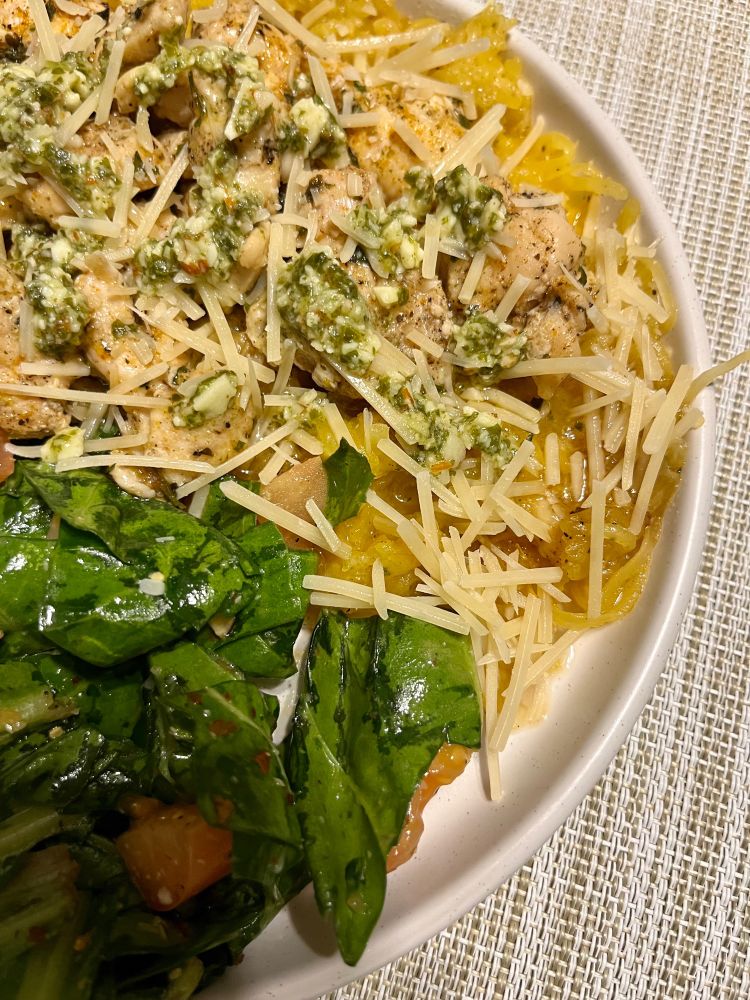 Тарілка їди: салат з зелені та помідору, гарнір з гарбуза, курка, тертий сир пармезан, соус песто. Виглядає хаотично і незрозуміло.