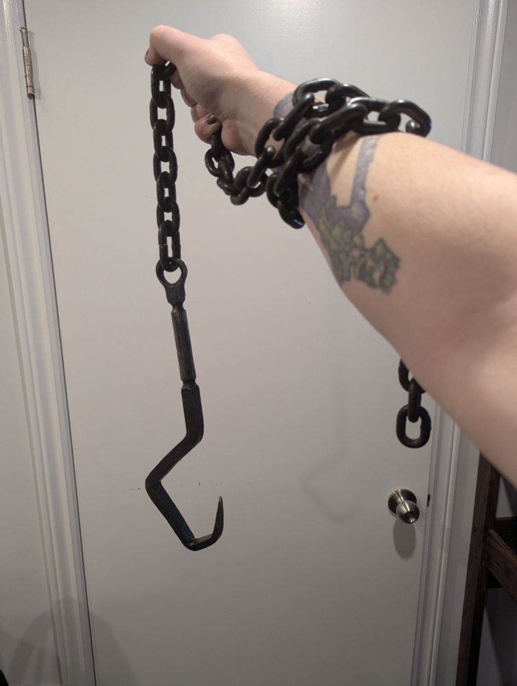 METAL HOOK ON A CHAIN WRAPPED AROUND CLOVE'S ARM 