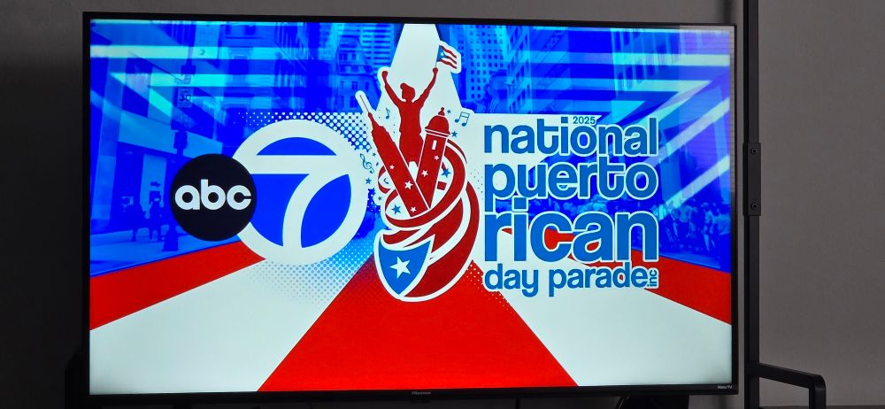 A television screen showing the title card for the ABC7 2025 National Puerto Rican Day Parade in NYC.