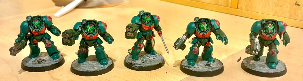 A squad of space marine terminators, in green armor with red trim.