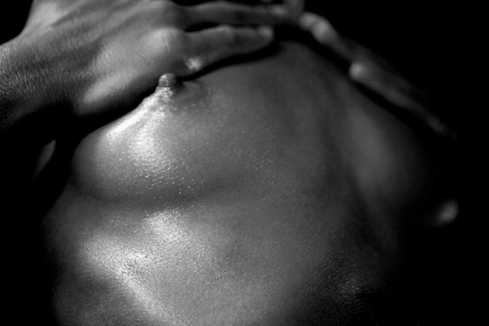 Closeup of female small breasts, her hands touching them. In black and white.