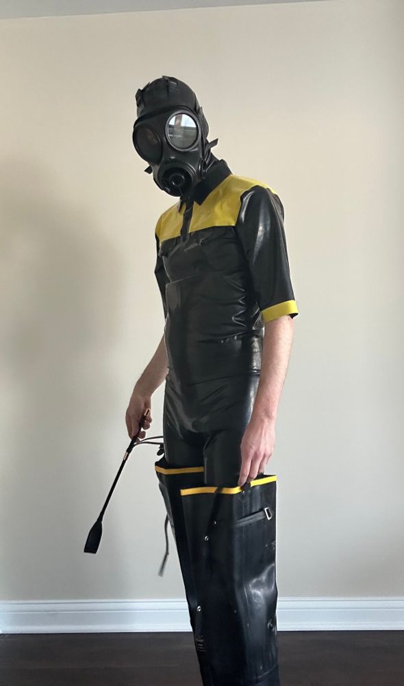latex drone with riding crop, and in a yellow and black rubber riding outfit. 