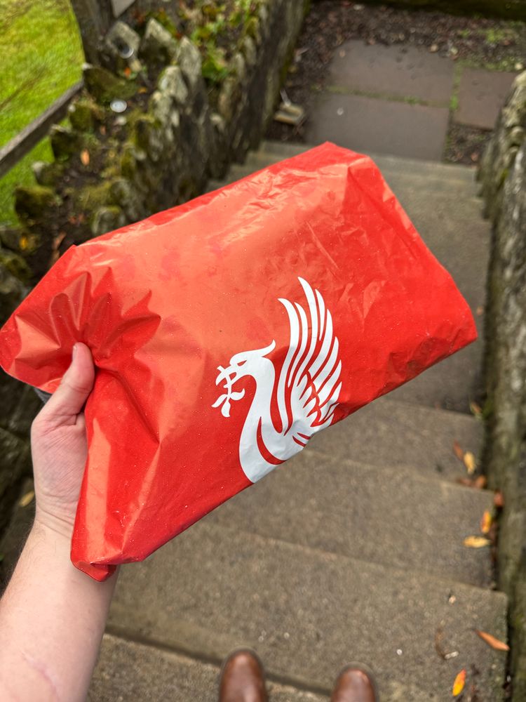 A person holding a bag with the Liverpool football club logo on it