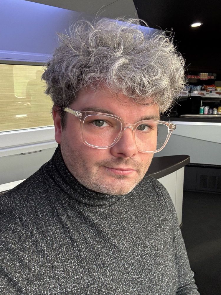 A selfie of a man with grey hair and glasses