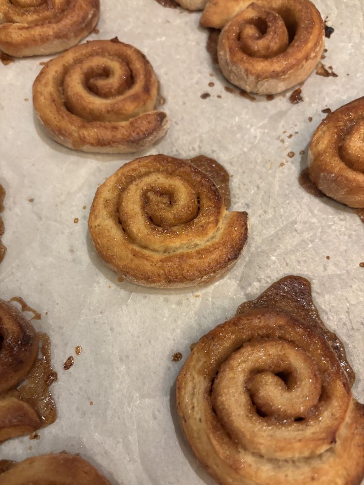 Opgerolde kaneelbroodjes op wit bakpapier 