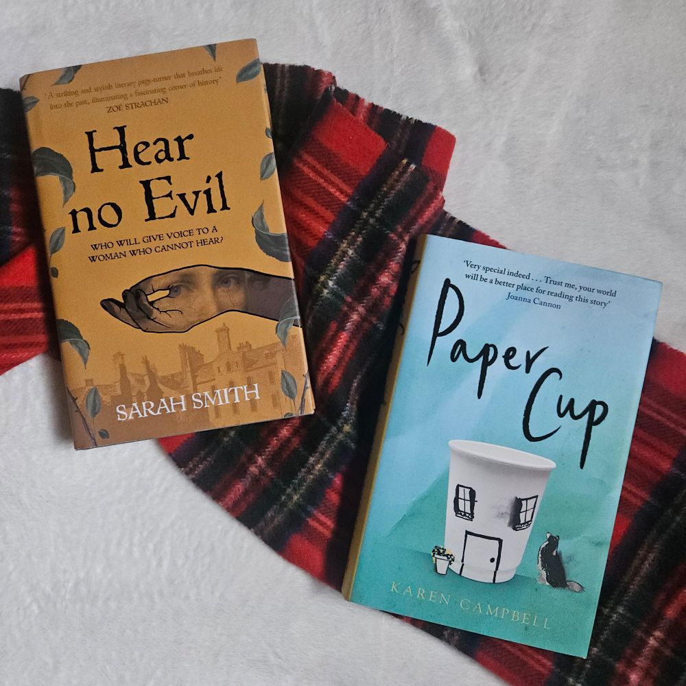 Image of two books - Hear No Evil & Paper Cup - lying on a red tartan scarf