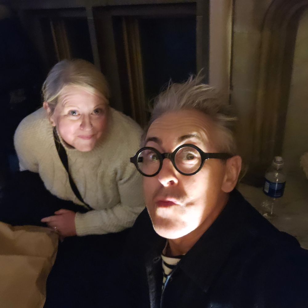 Atmospheric selfie of me and Alan Cumming. I'm wearing a white jumper and AC is in a black top and round black glasses