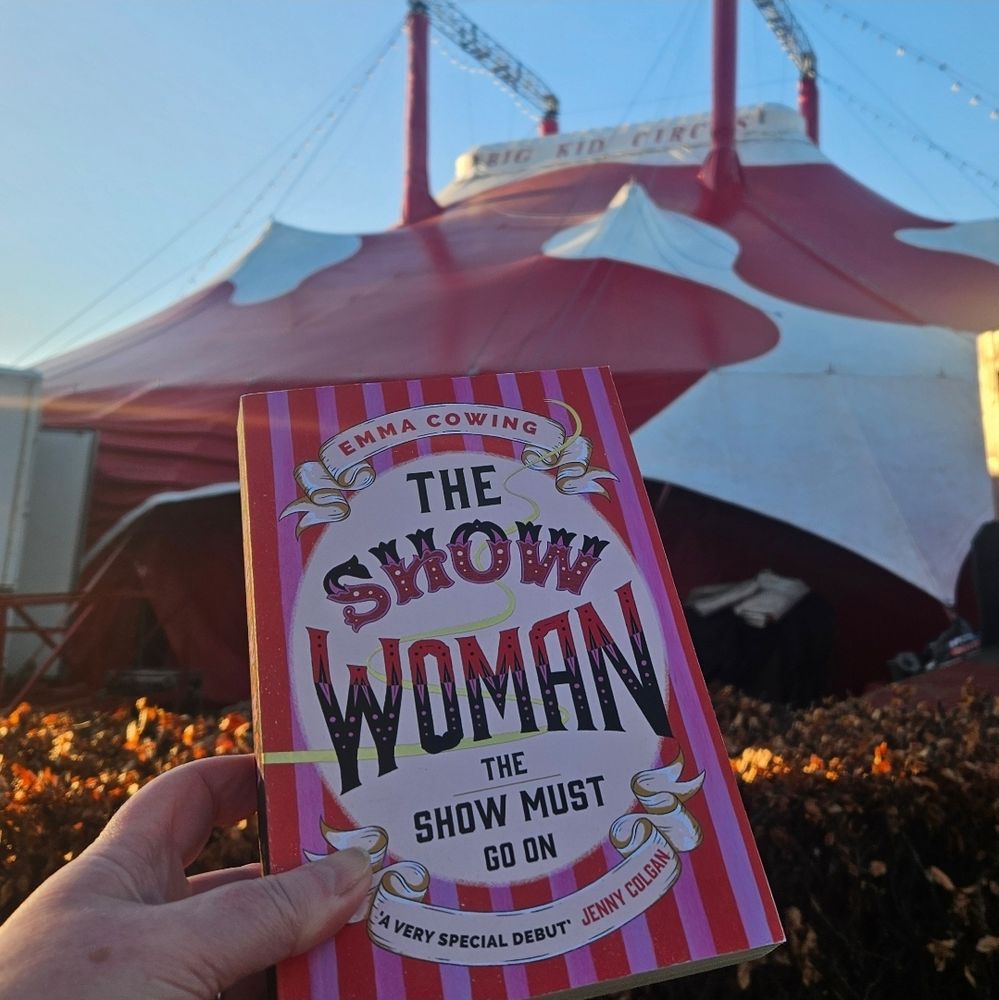 A copy of The Show Woman book held up in front of a circus big top