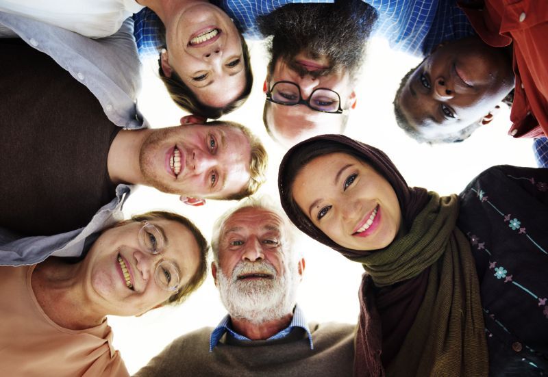 Image: A diverse group of people leaning in and looking down into the camera below.