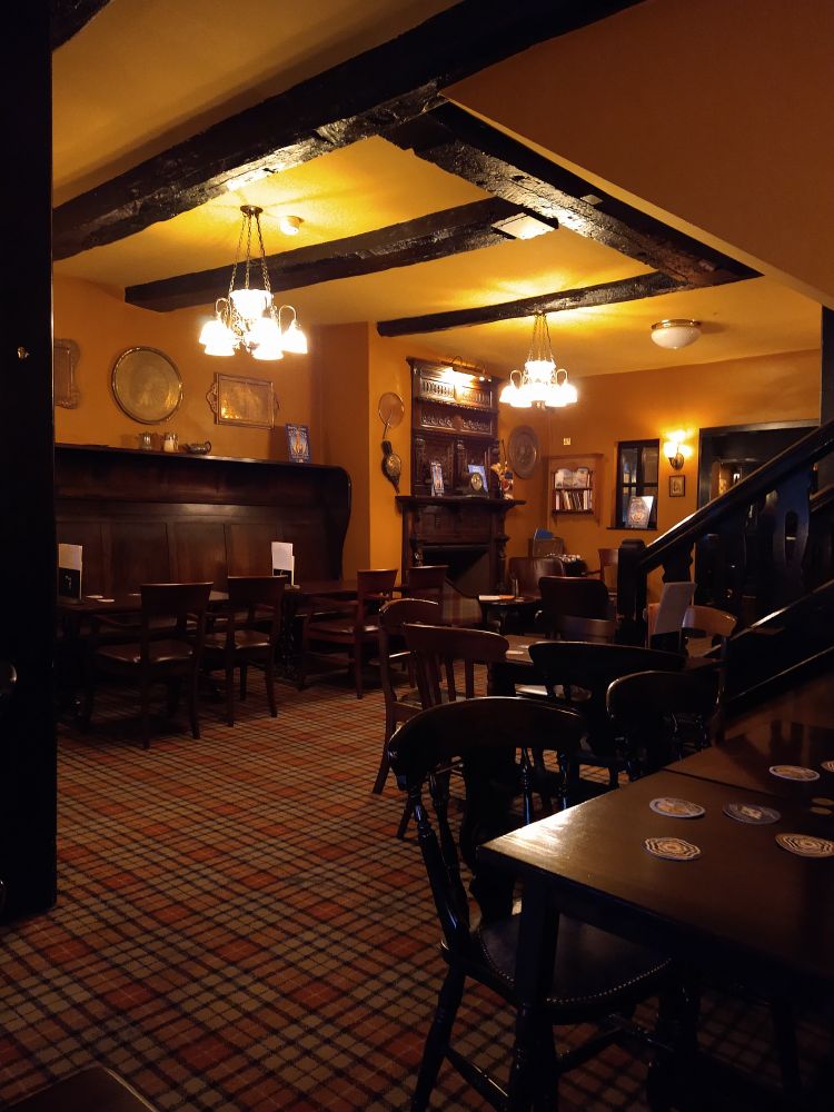 The cozy, timbered interior of a 17th century pub. It's all yellows and ochres and browns. Warm and inviting.