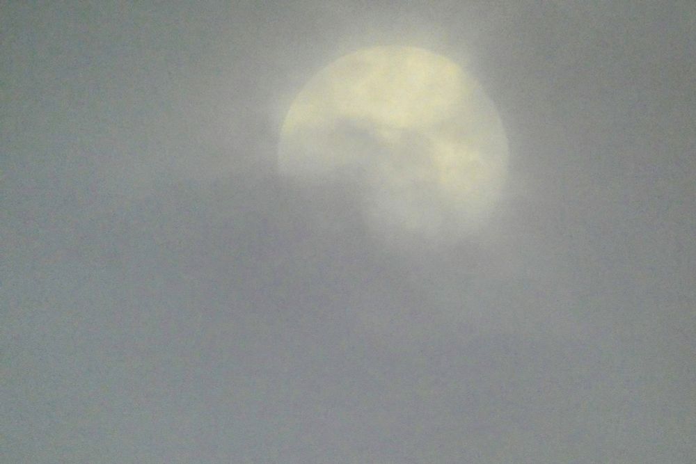 A large sun is shining through the clouds.