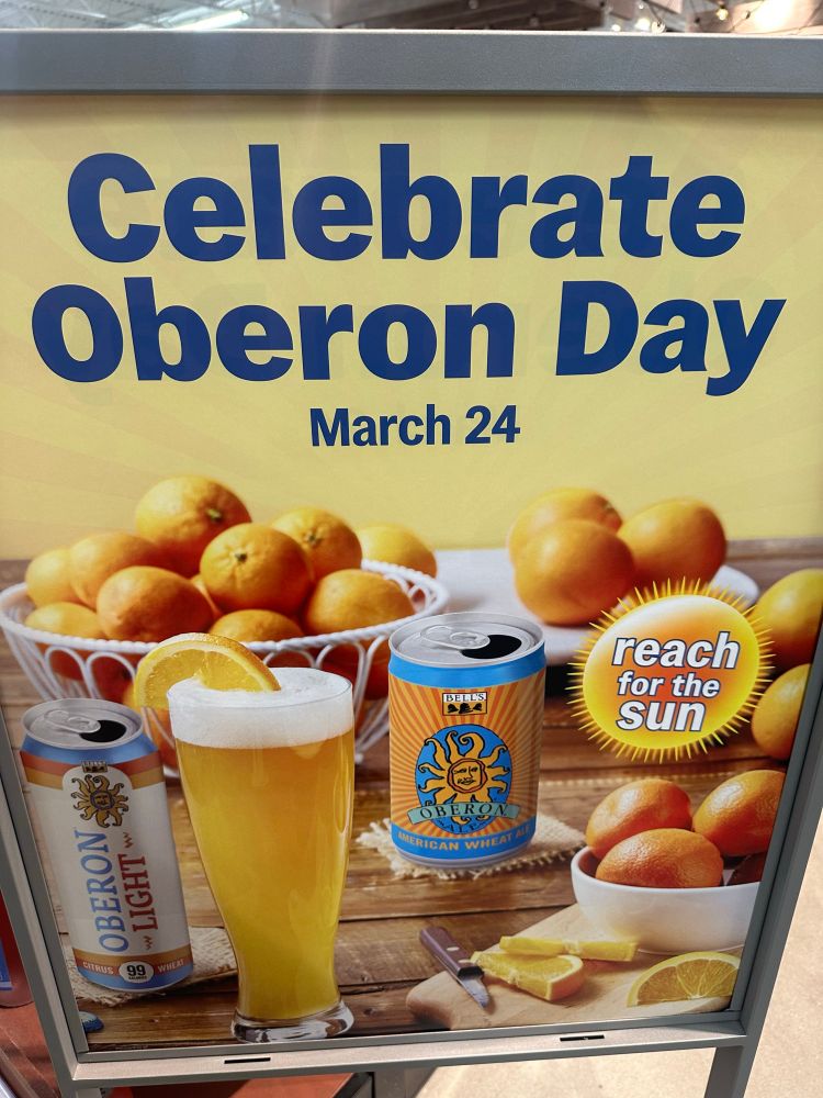 A sign that says “Celebrate Oberon Day March 24” with Oberon beer and oranges in the background